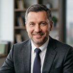 Портрет уверенного российского бизнесмена с дружелюбным взглядом на нейтральном размытом фоне студии